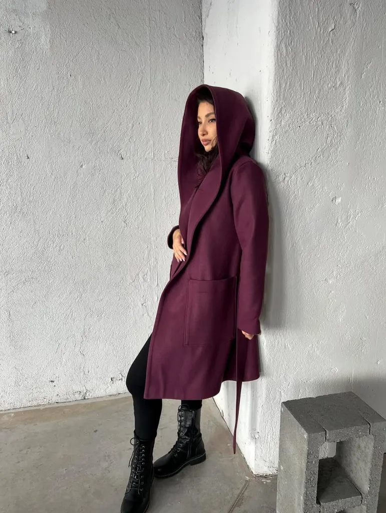 A hooded coat with a structured, architectural silhouette in a muted tone.