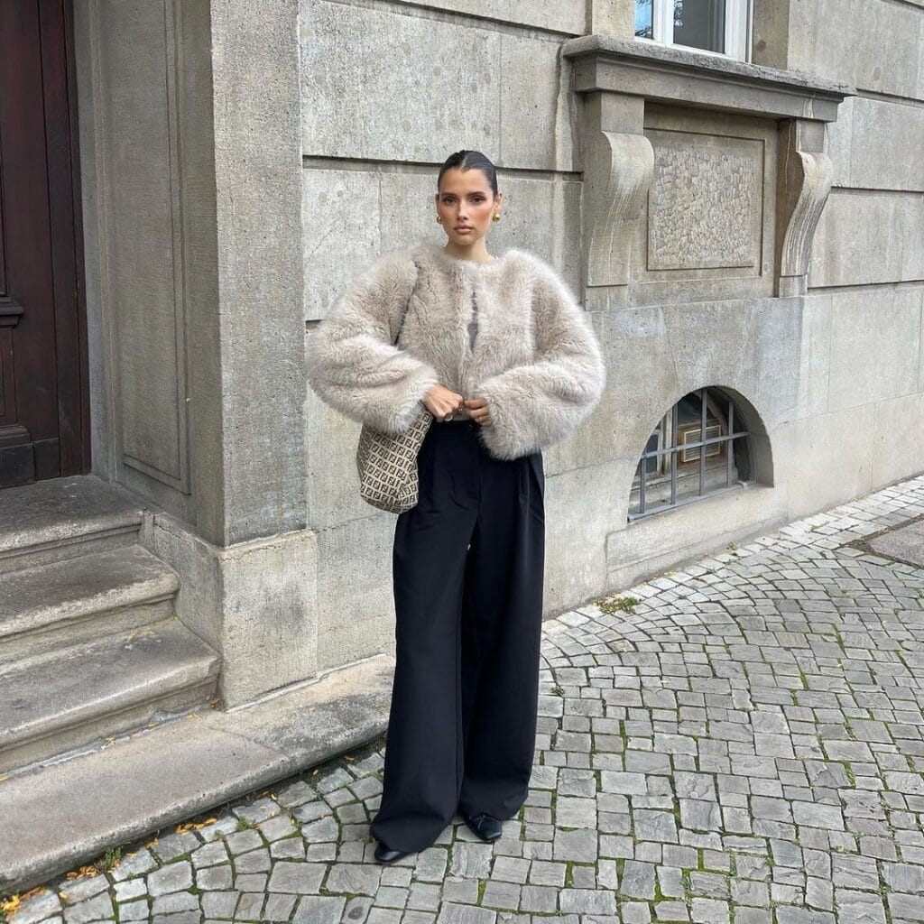 Woman in a fuzzy jacket and wide-leg trousers, demonstrating soft power dressing.