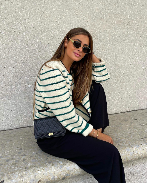 A woman in a relaxed striped knit and black trousers.
