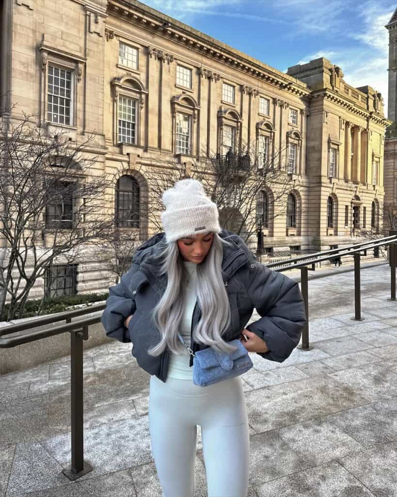 Woman in icy-toned athleisure with a puffer jacket and beanie, embodying sporty chic.