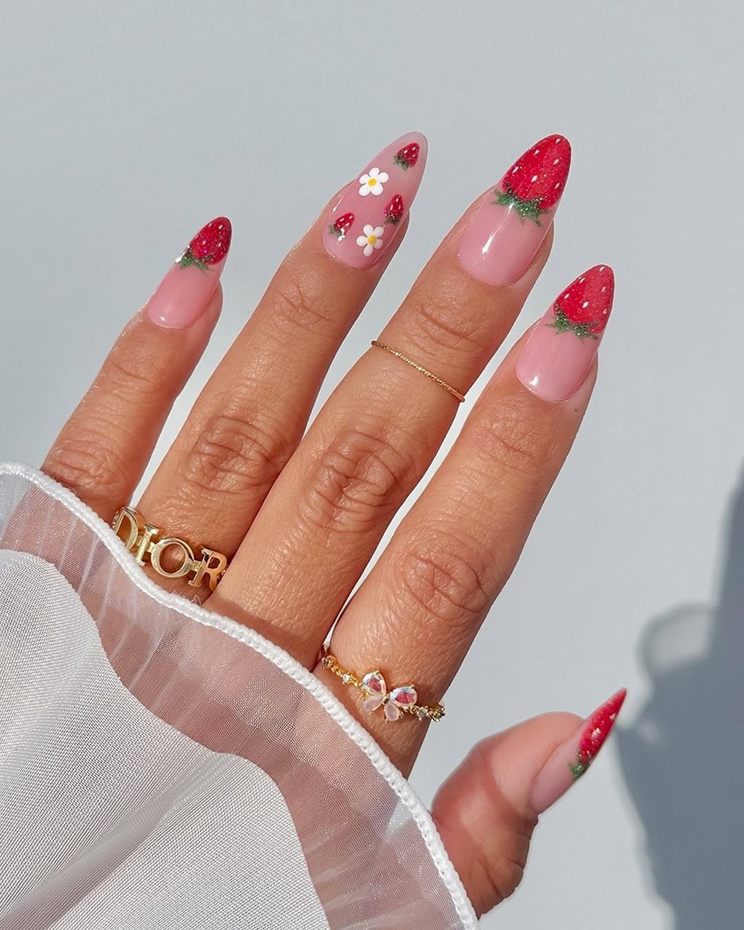 Sheer pink nails with tiny strawberries and floral details