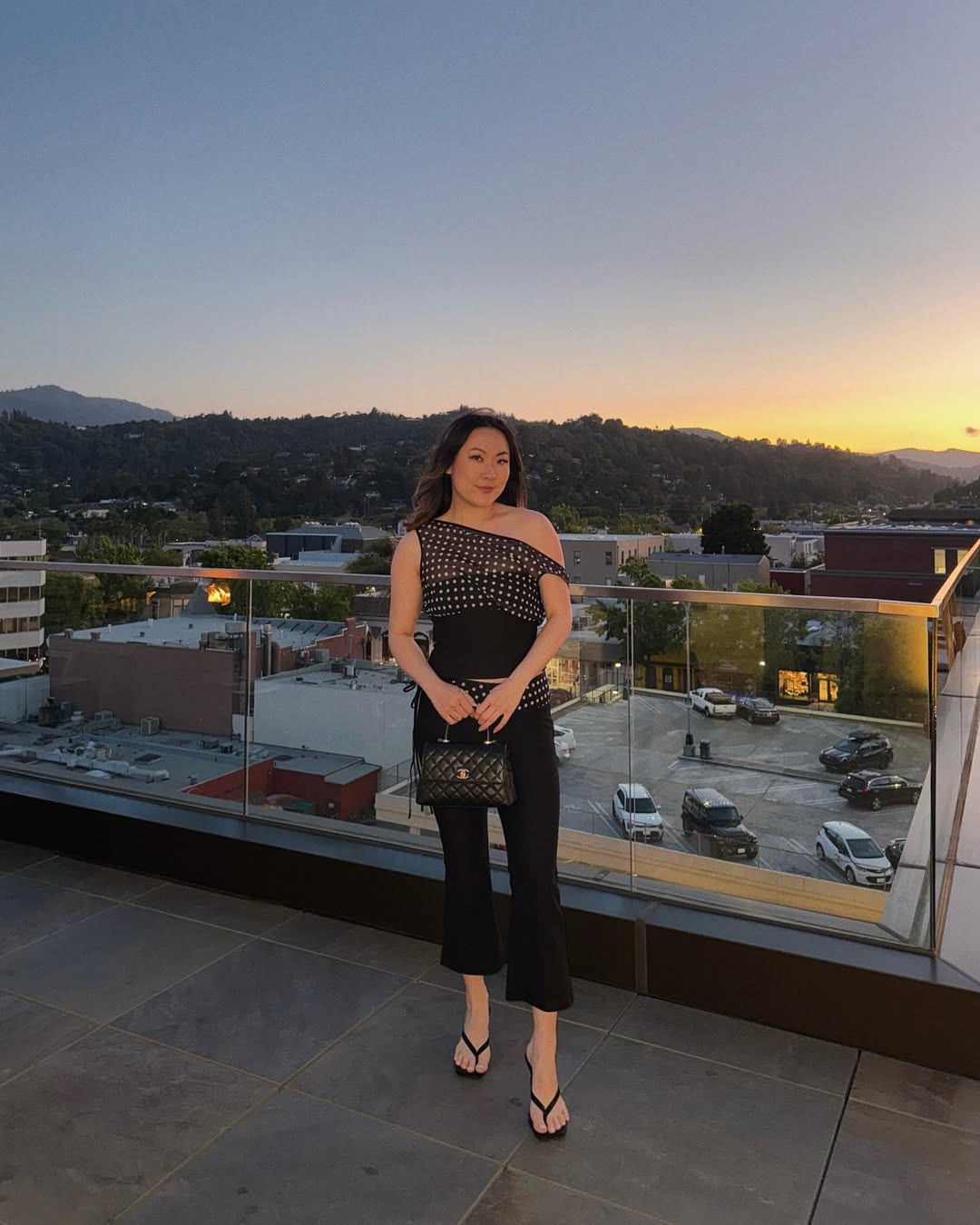 A sleek one-shoulder black dress with embellishments against a city skyline.