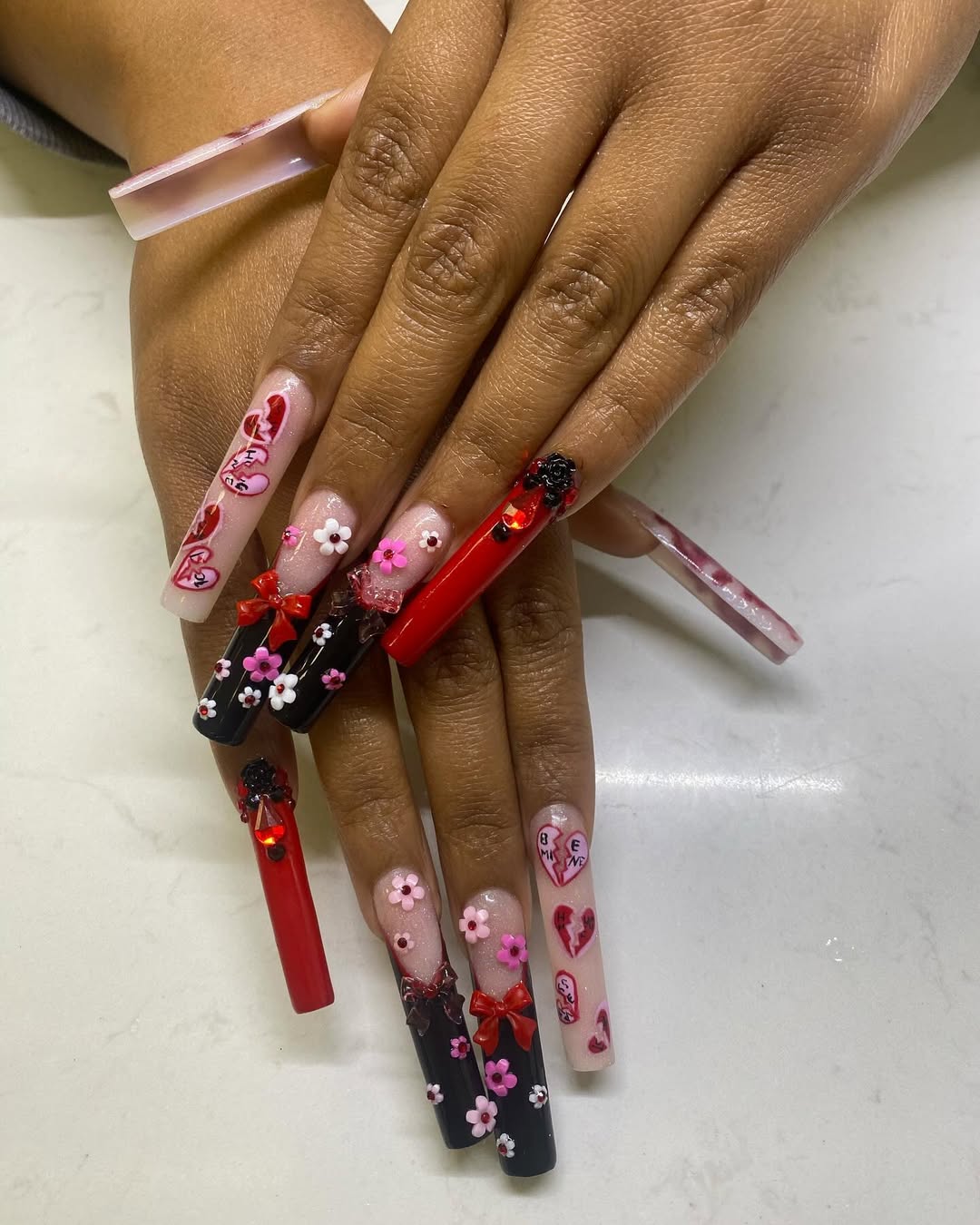 Bold red nails with tiny florals and sculpted accents