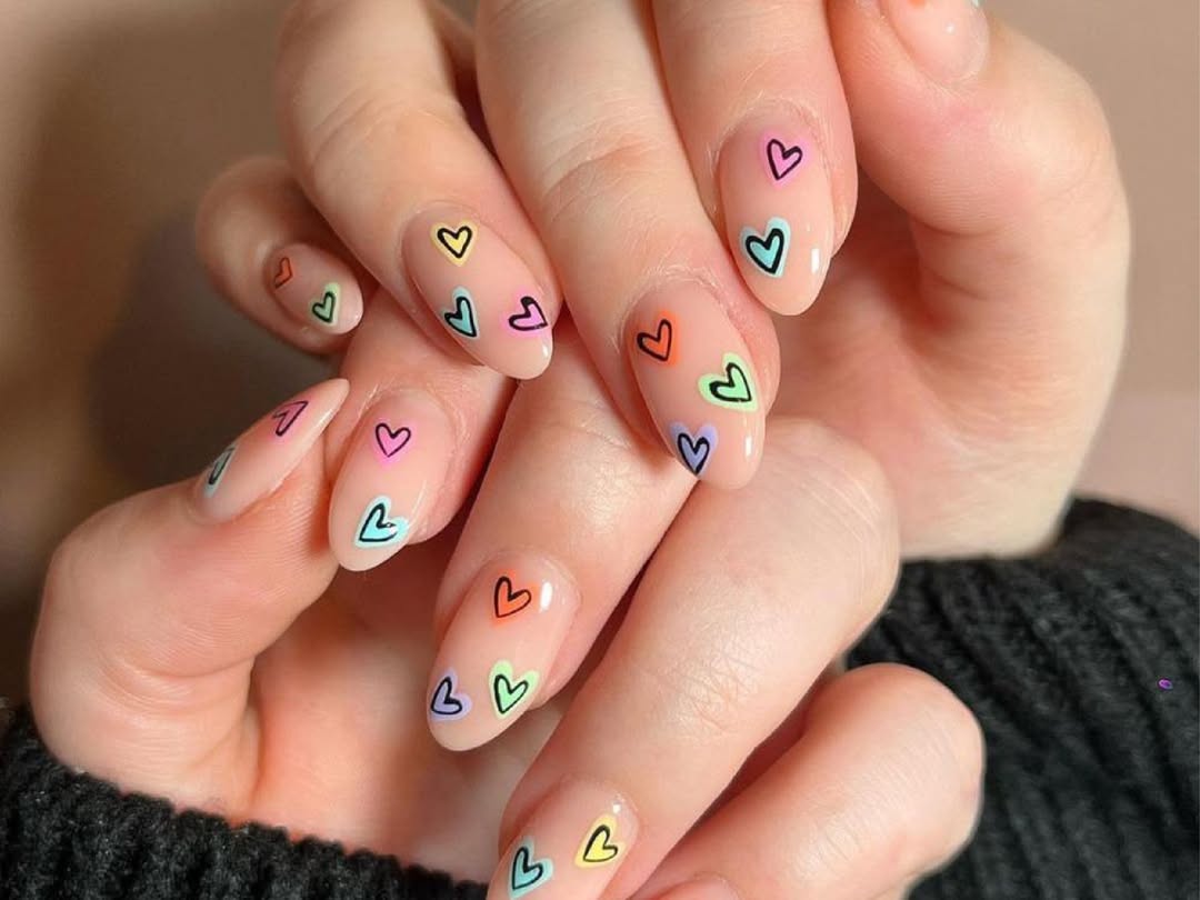 Soft nude nails with playful multicolor hearts