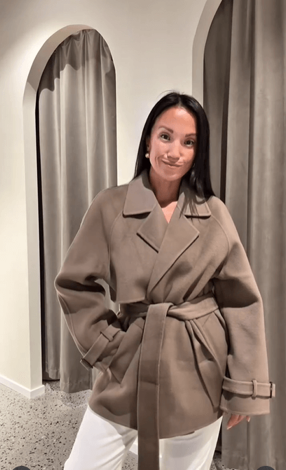 Woman in a belted coat and neutral tones, presenting a timeless tailored neutral outfit.