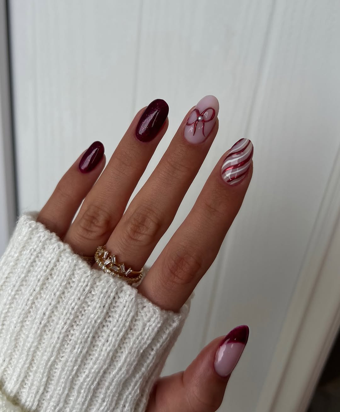 Berry and blush nails with red ribbon and candy cane stripe accents.