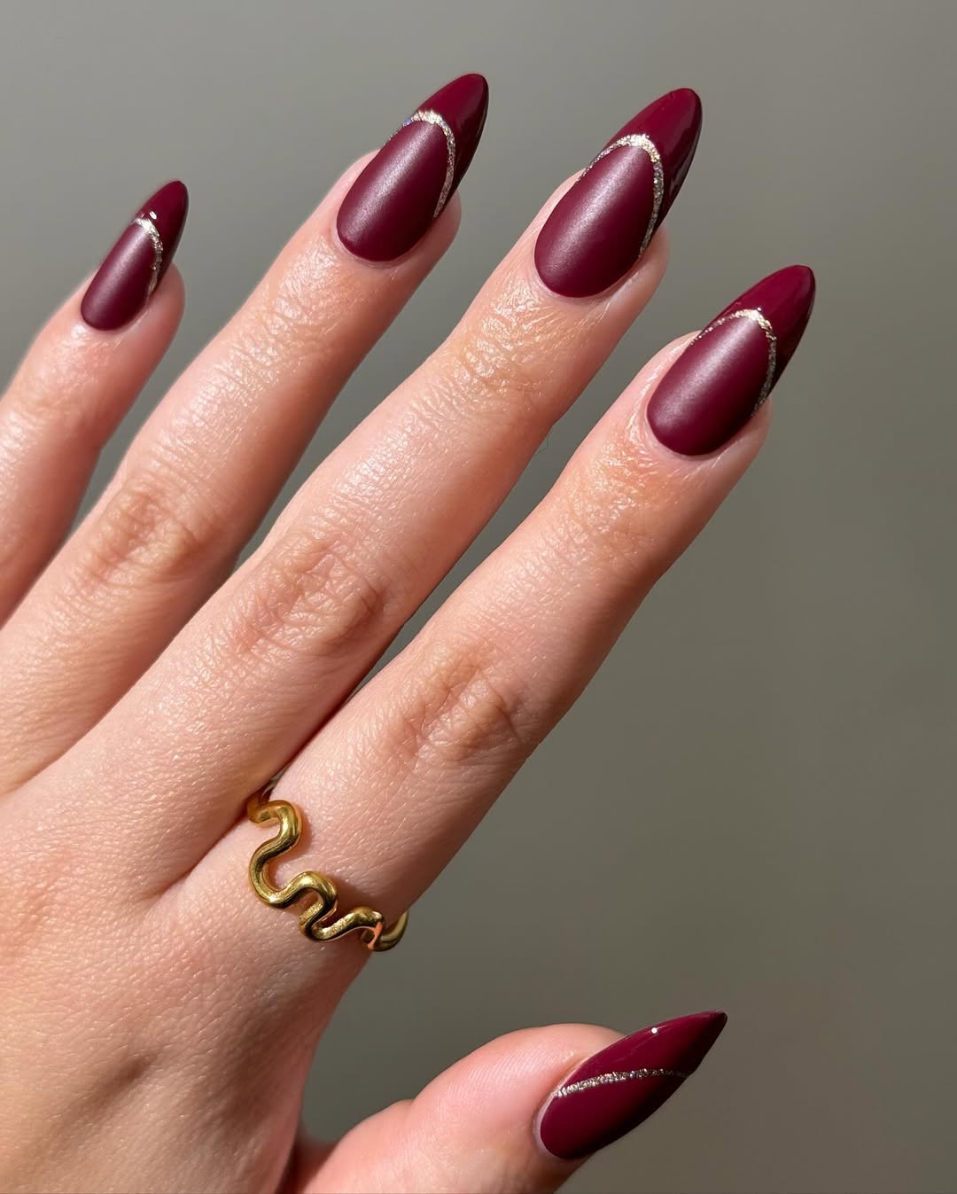 Matte burgundy nails with glossy cut-out French tips and silver glitter outline