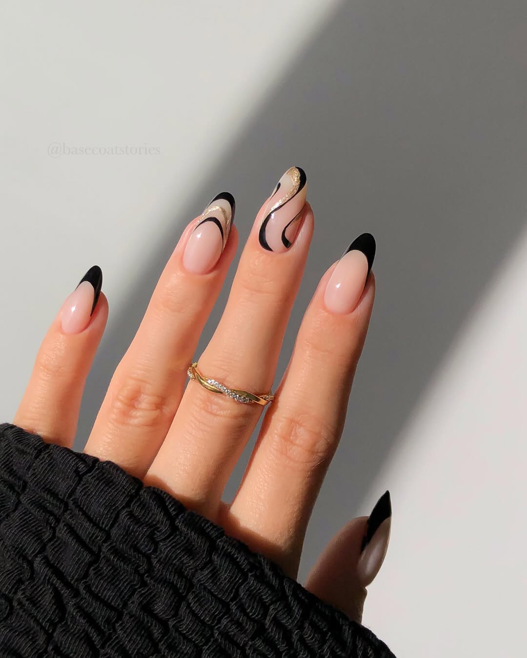 Black French tips with gold swirl accents on a nude base