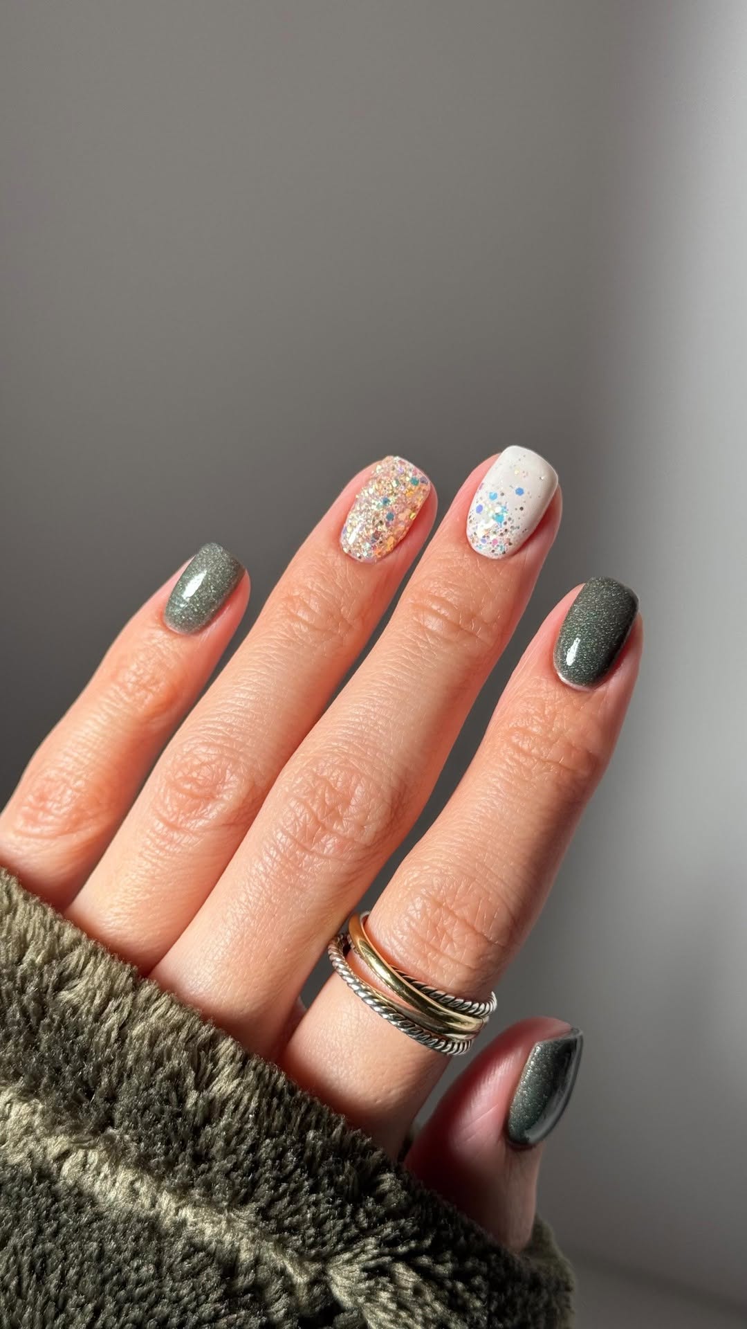 Deep green shimmer nails with glitter and confetti-like accents.