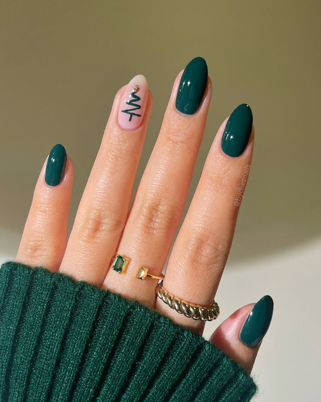 Deep emerald green nails with a nude accent featuring a simple line-drawn Christmas tree and gold star.