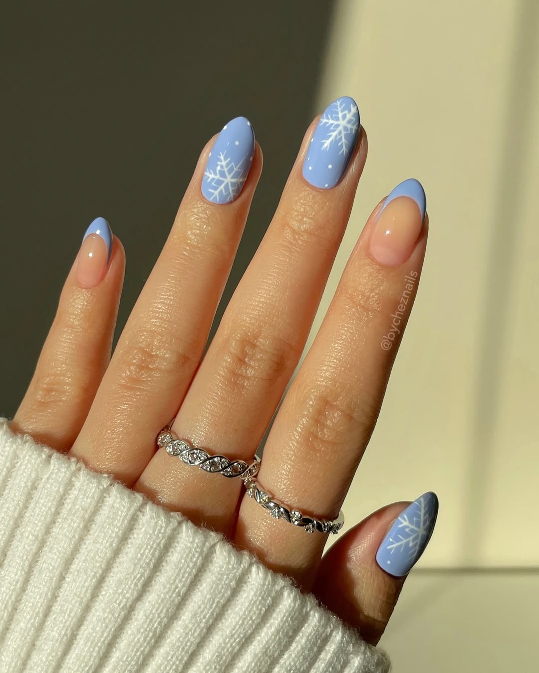 Icy blue nails with white snowflakes and blue French tips.
