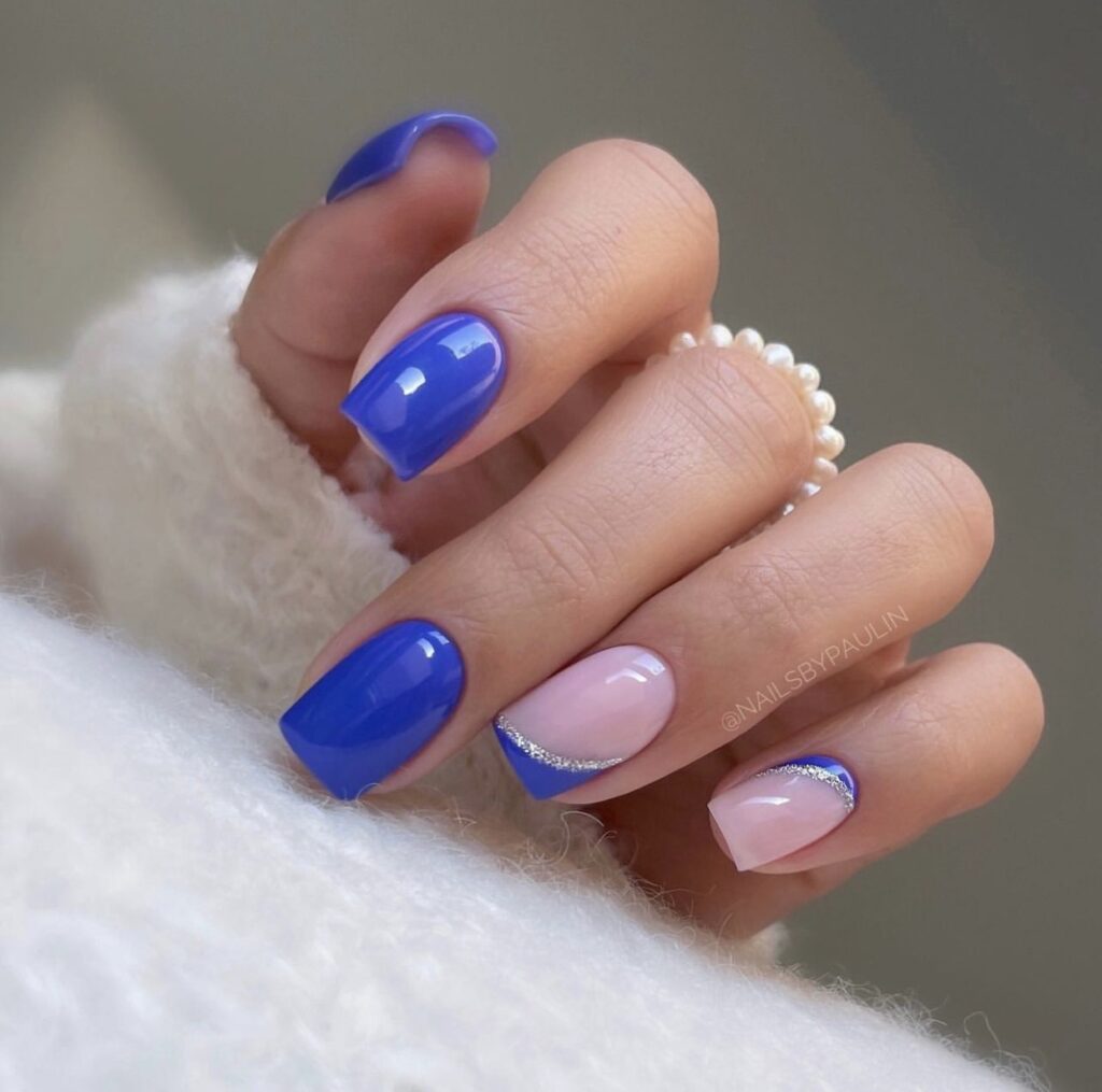 Short winter nails in a bright blue polish with a simple design.