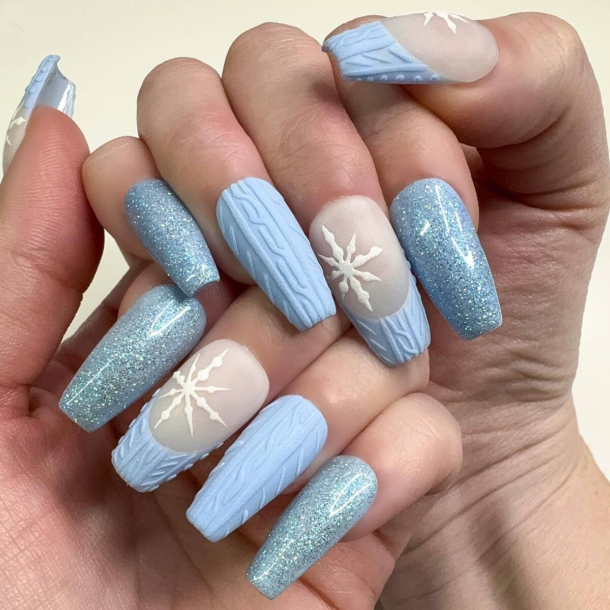 4. Icy Blue Sweater Nails with Snowflake Charm