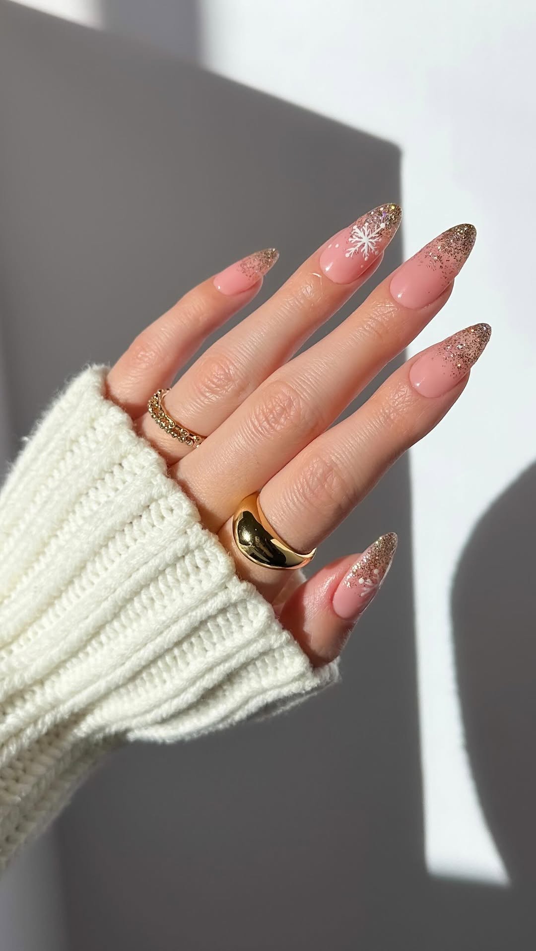 Gold glitter tips with a soft pink base and white snowflake details.