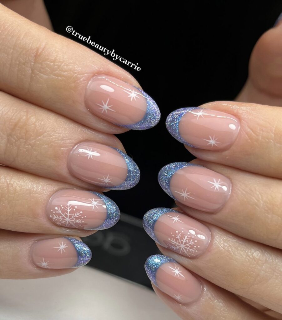 Short winter nails with sparkly blue French tips and snowflakes.