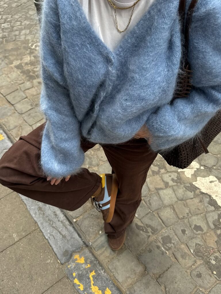 Blue fuzzy cardigan with brown trousers and sneakers.