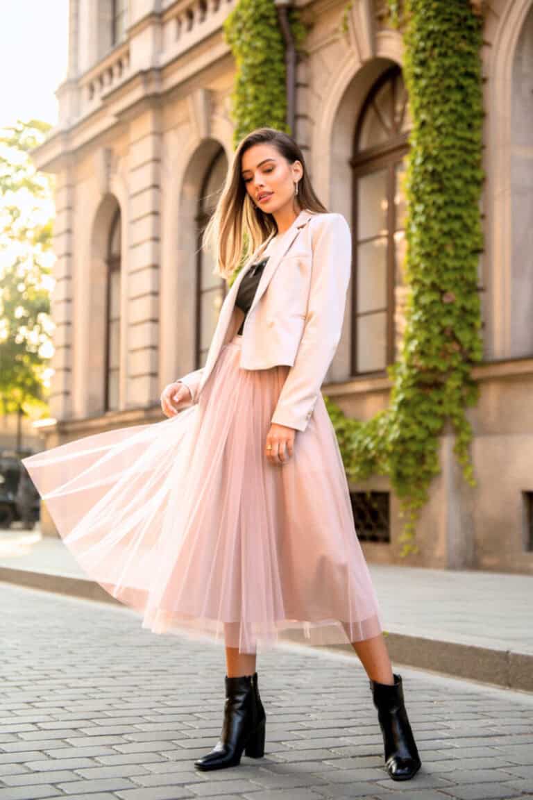 A person wearing a tulle midi skirt with ankle booties and a cropped jacket.