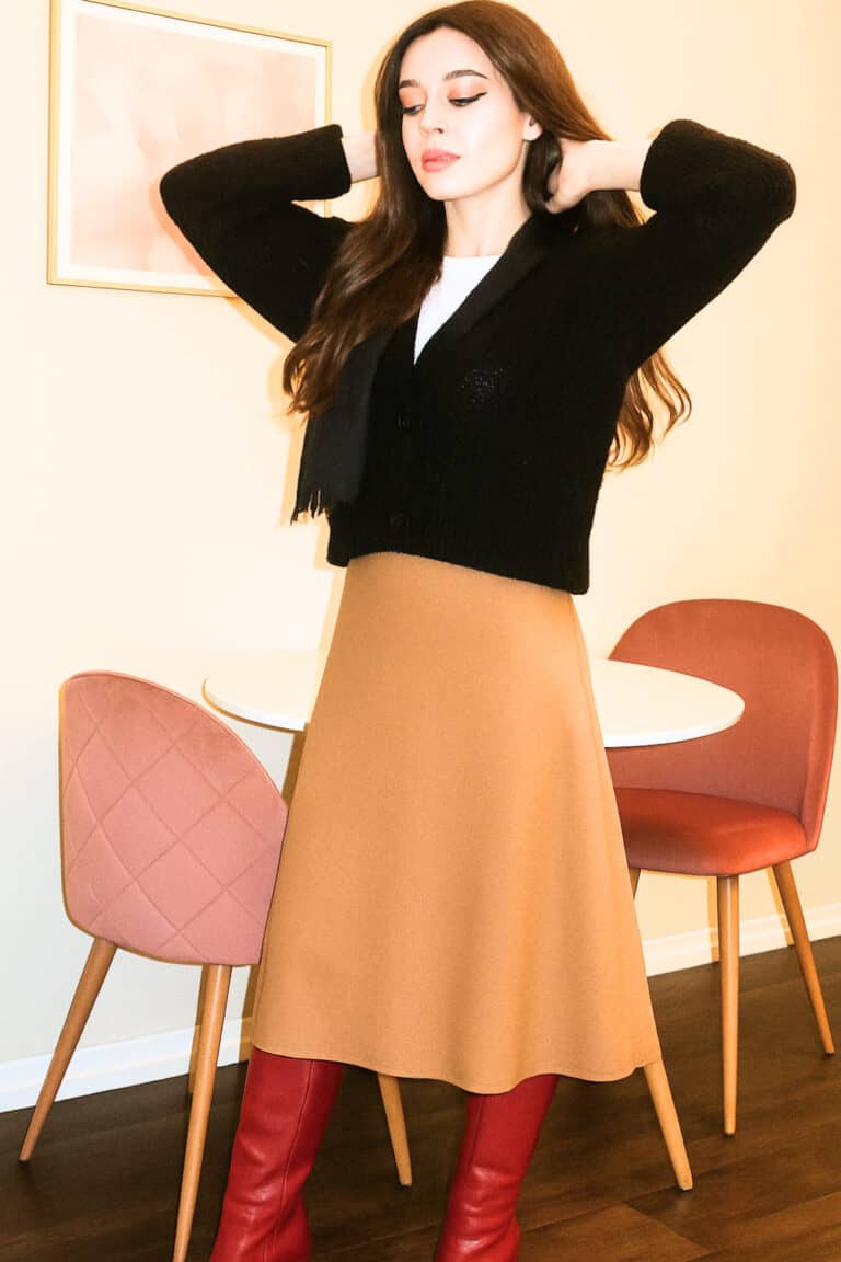 A person wearing a flowy maxi skirt with heeled boots and a fitted sweater.