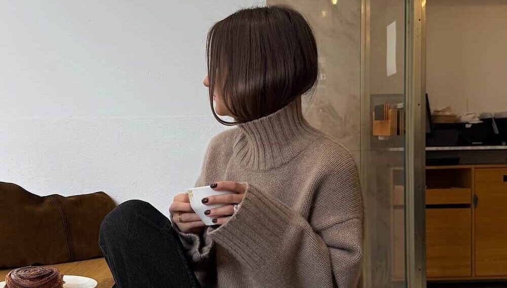 a woman wearing black jeans, black loafers, and a brown turtleneck