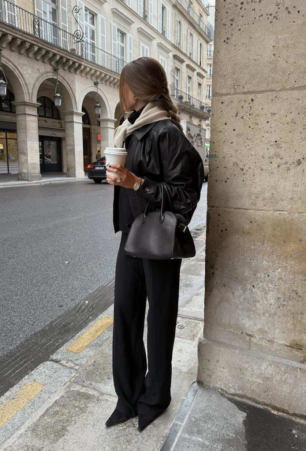 a woman wearing black slacks, a leather jacket, heels, and a cream scarf