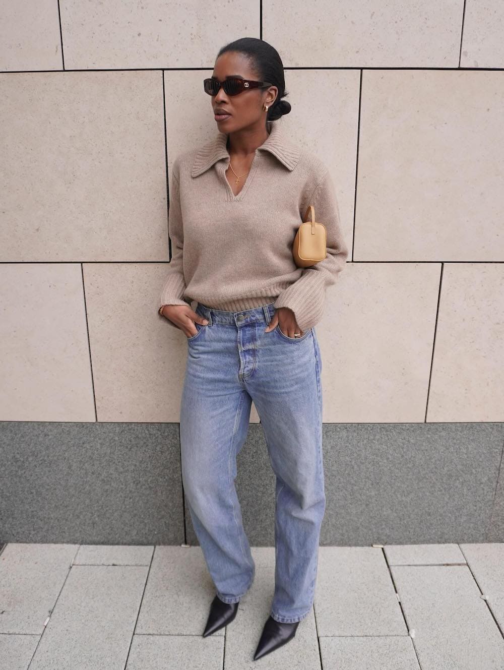 a woman wearing blue jeans, a v neck sweater, and heeled black boots