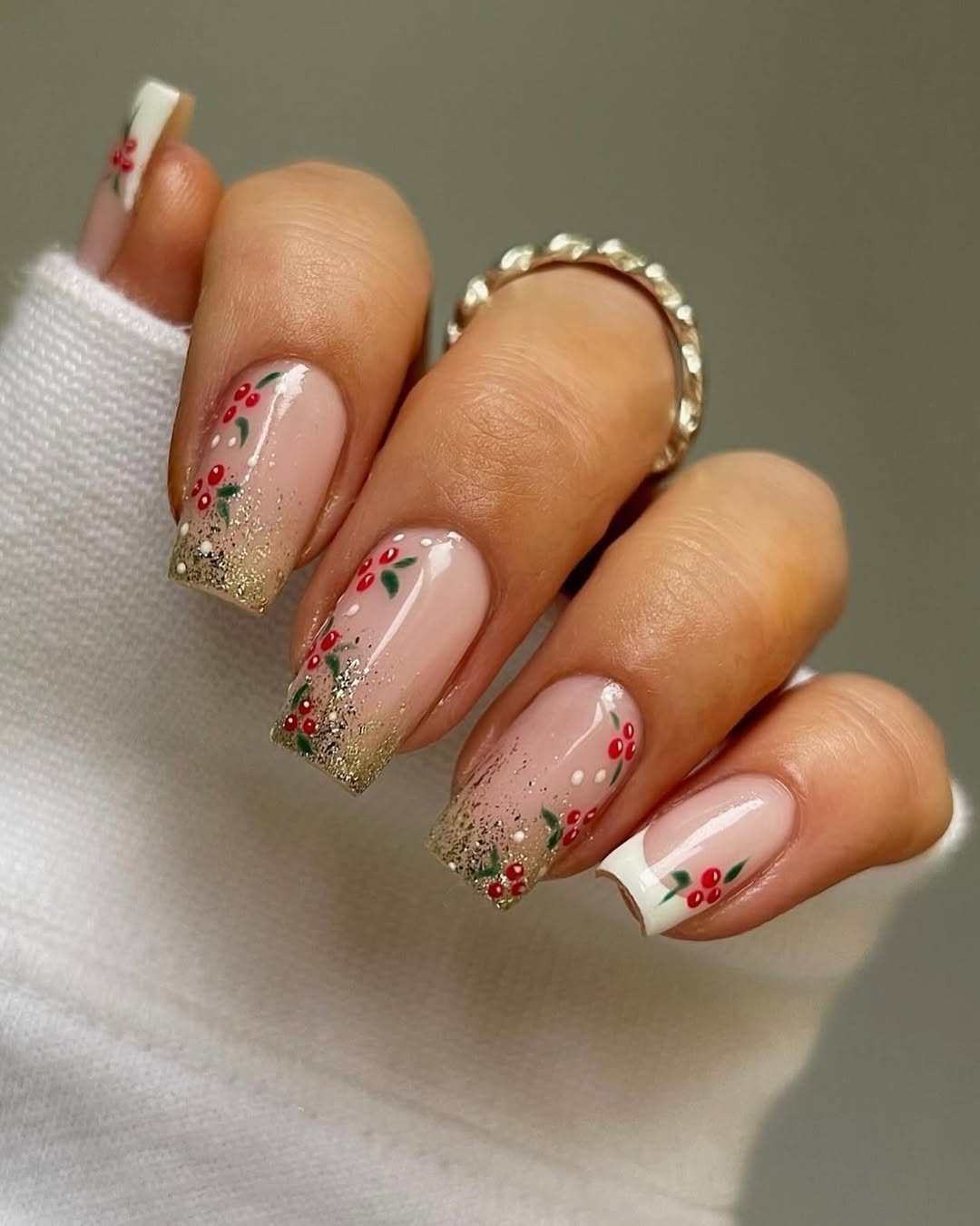 Soft square nails with gold glitter tips and tiny holly berry accents.