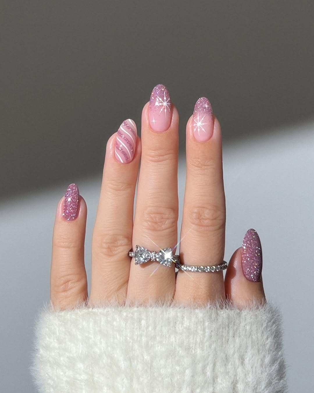 Dusty pink glitter French tips with white star accents and a candy stripe accent nail.