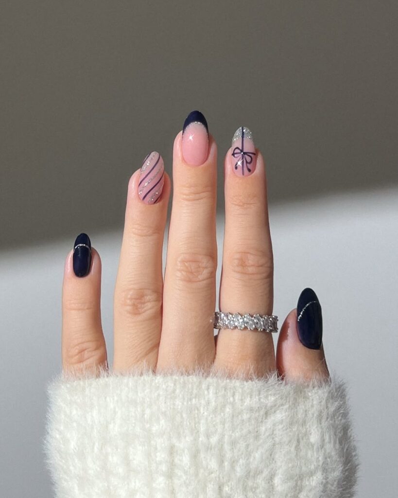 Deep navy nails with soft pink accents, glitter tips, and striped designs.