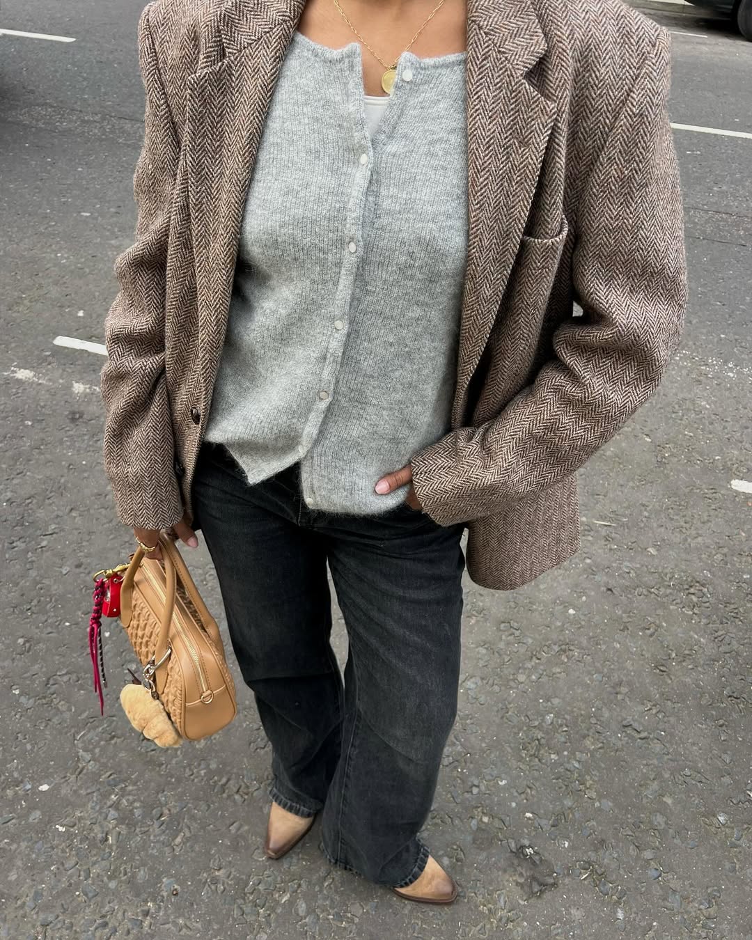 Grey cardigan under a herringbone blazer with washed black jeans.