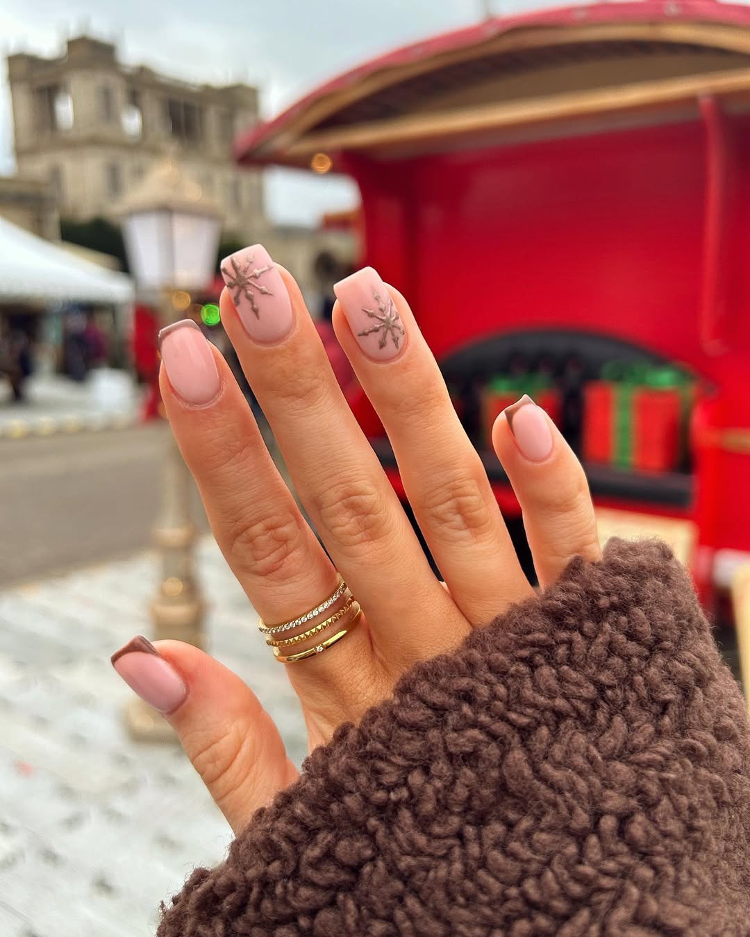 Brown nails with lighter brown French tips and snowflake details.