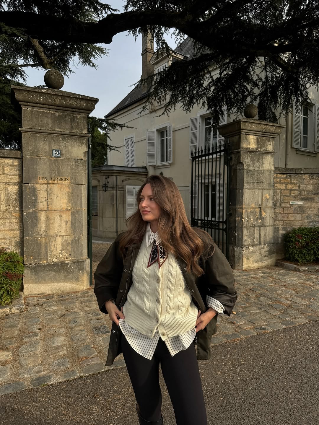 Waxed jacket, striped shirt, cable-knit vest, and riding boots