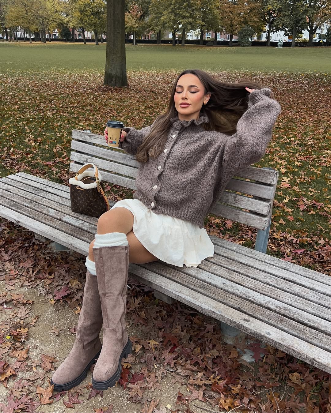Taupe ruffled cardigan with a cream mini skirt and knee-high boots.