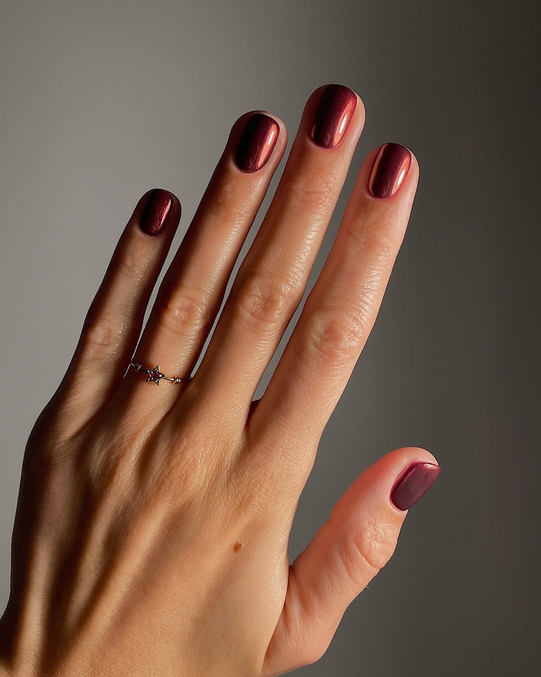 Berry red chrome nails with a mirror-like finish.