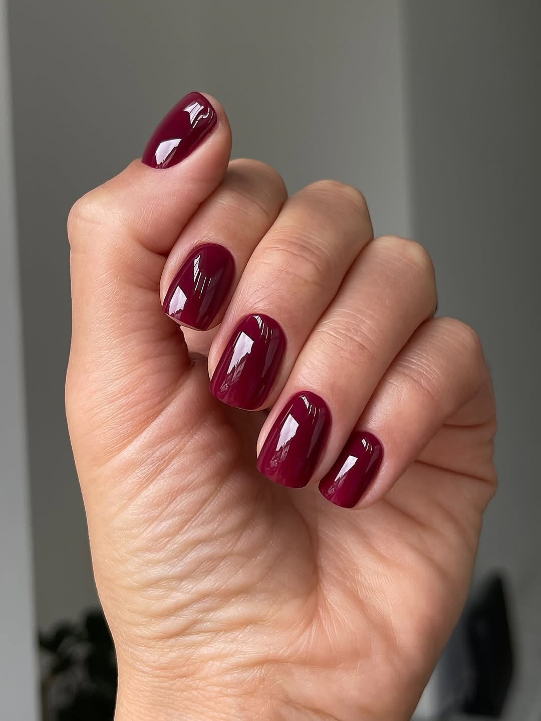 Deep cranberry gloss nails with a short rounded shape.