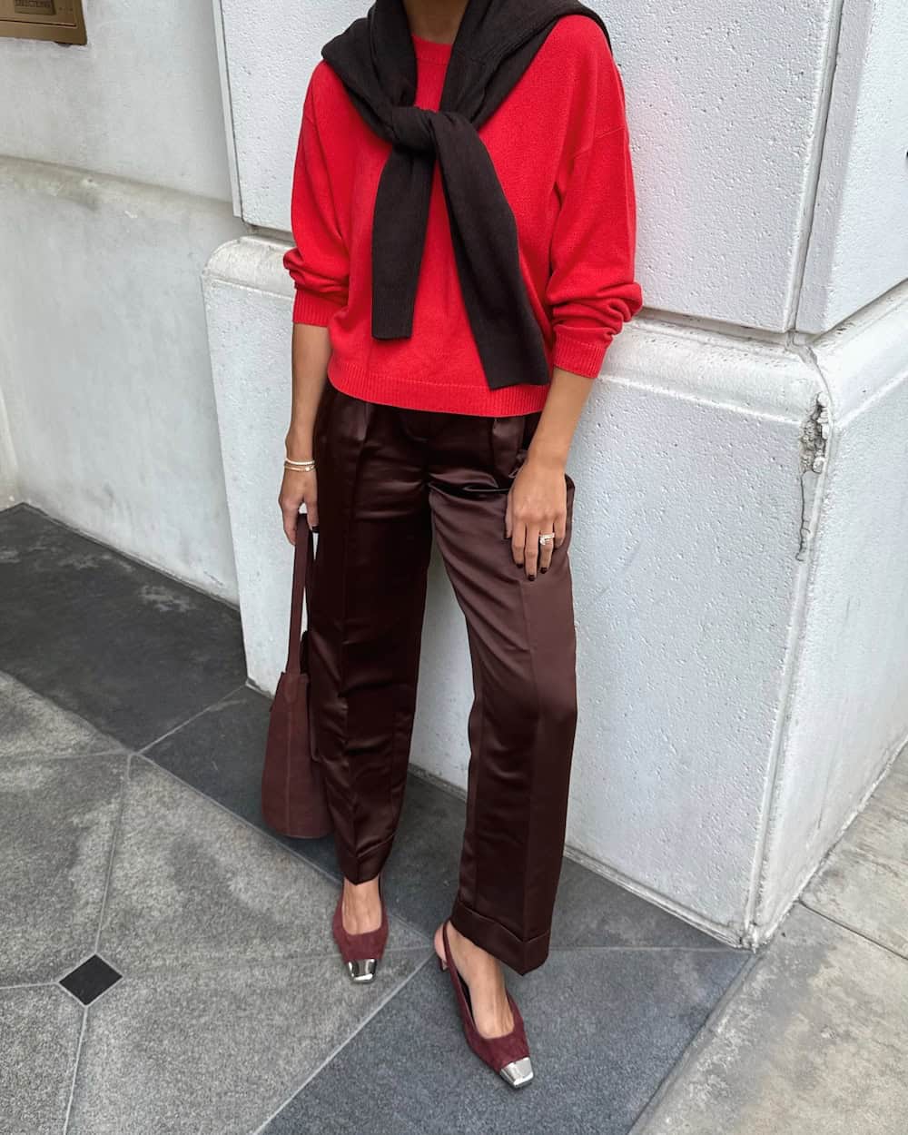 a woman wearing silky brown slacks, a red sweater, and brown and silver cap toe heels