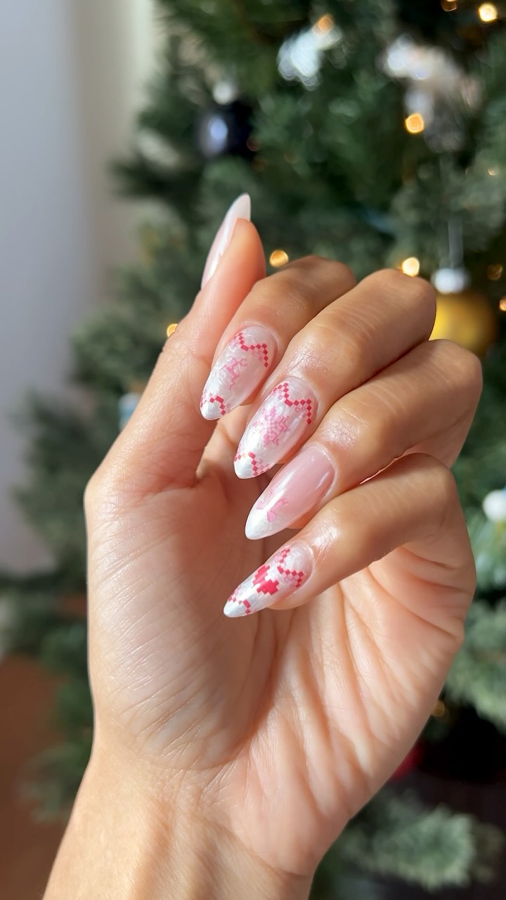 White French tips with a soft pink overlay featuring subtle red knit patterns and pixel snowflakes.