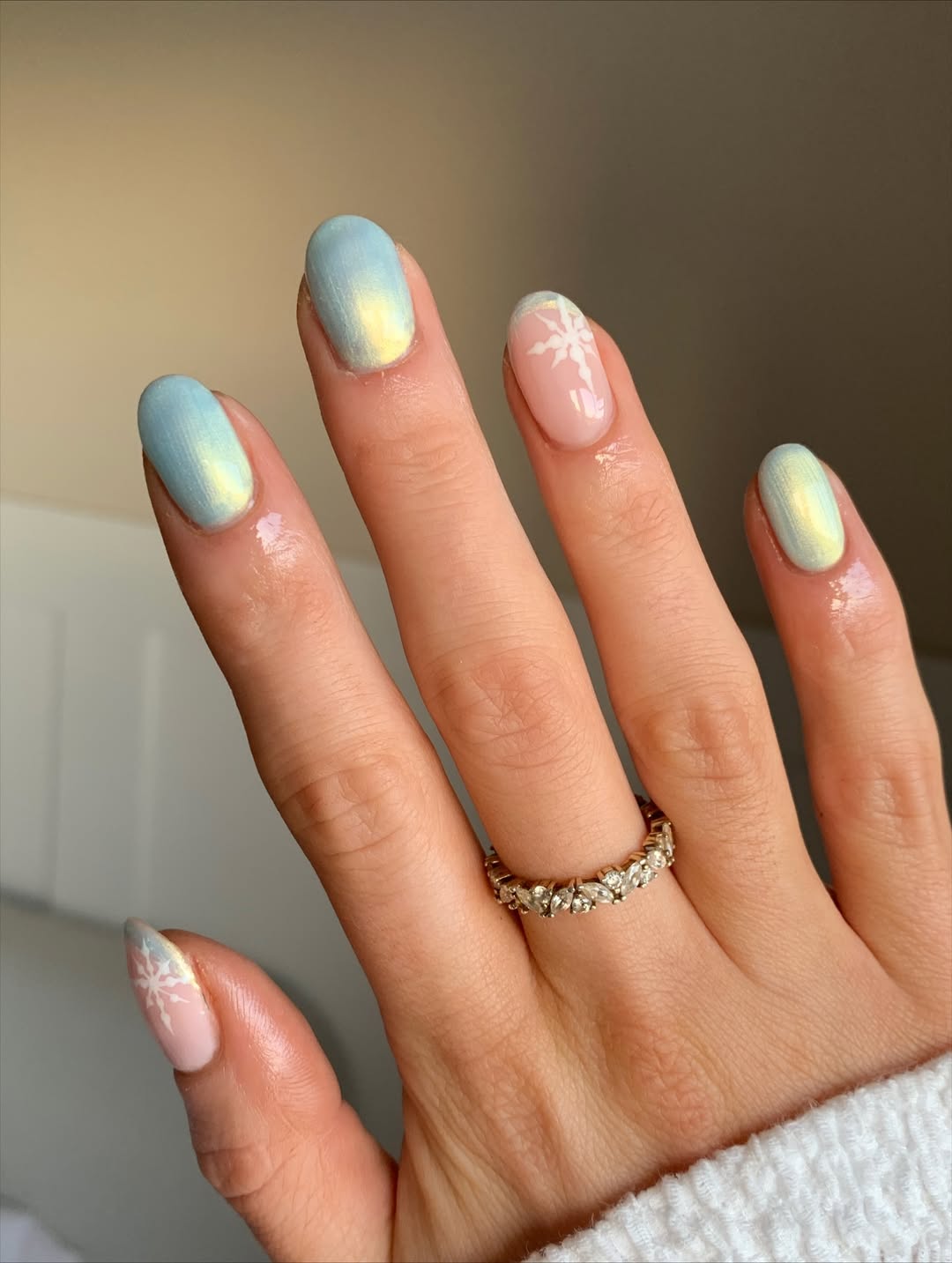 Pastel blue nails with blush accents and white snowflake tips.
