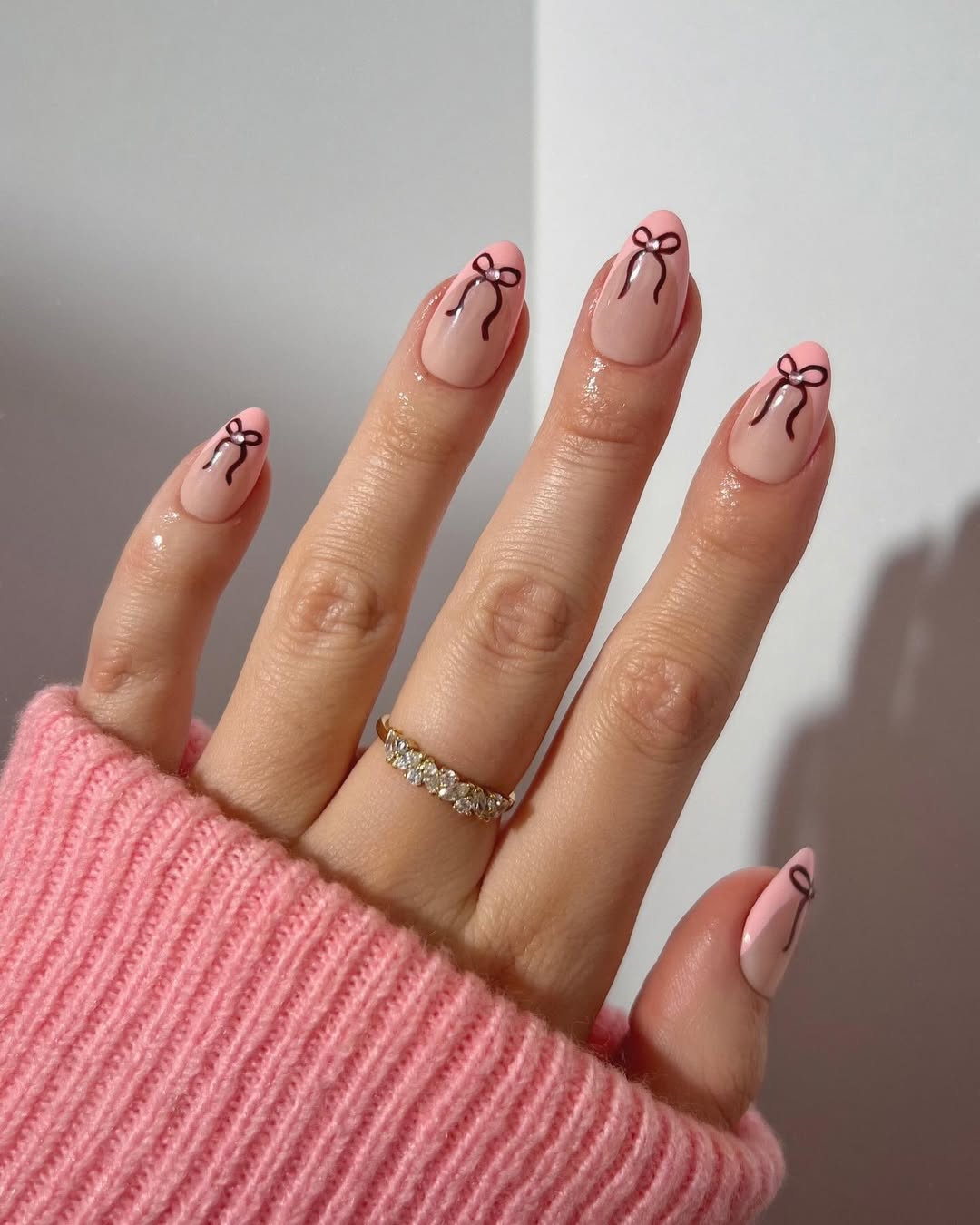 Soft pink nails with delicate, hand-painted bows as accent details.