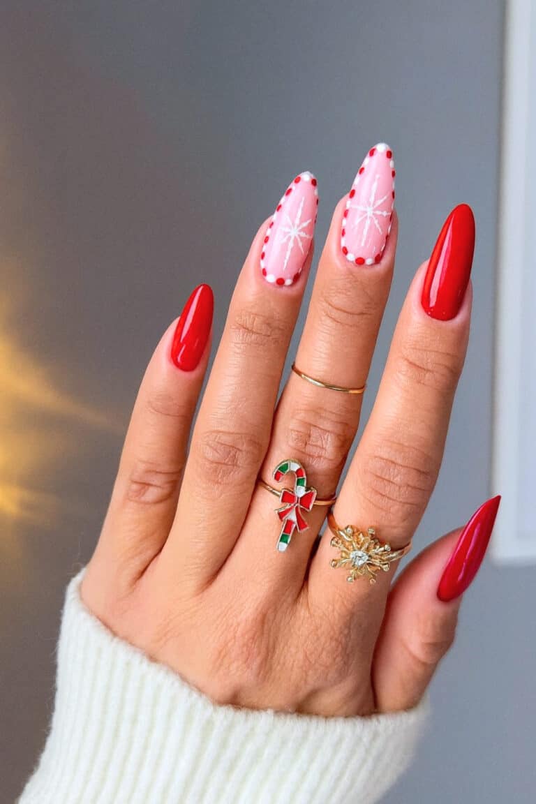 Glossy red nails with soft pink accent nails featuring dotted borders and white snowflakes.