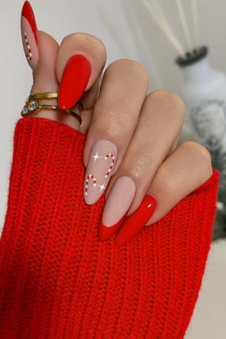 Bold red nails paired with a soft nude base featuring a candy cane accent nail with subtle sparkles.
