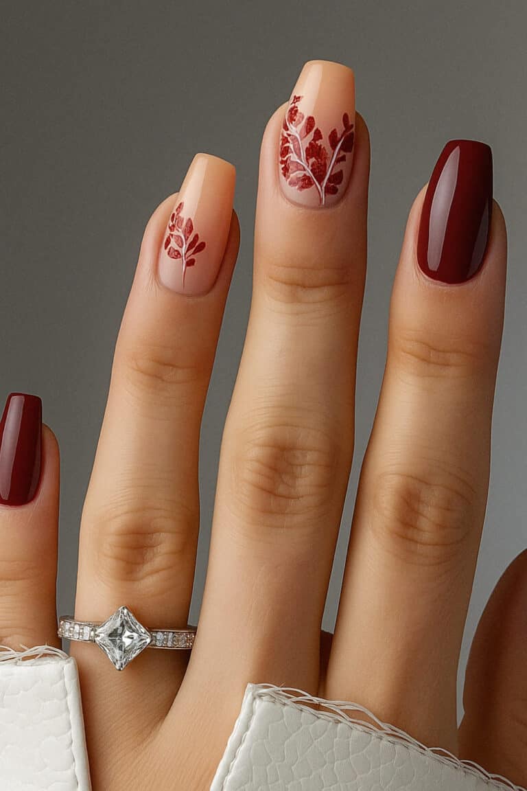 Soft nude base with deep red leafy accents and glossy wine red nails