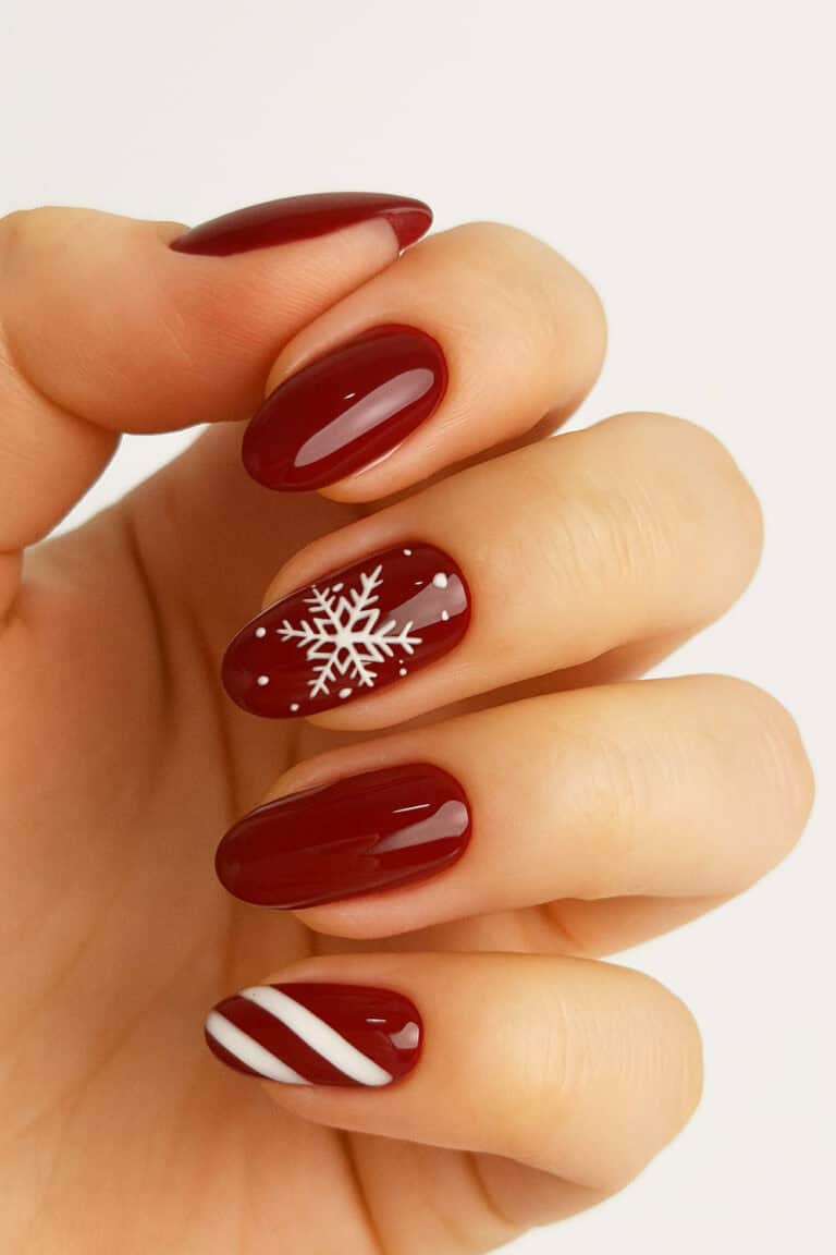 Glossy rich red nails with a tiny white snowflake and candy cane accent nail