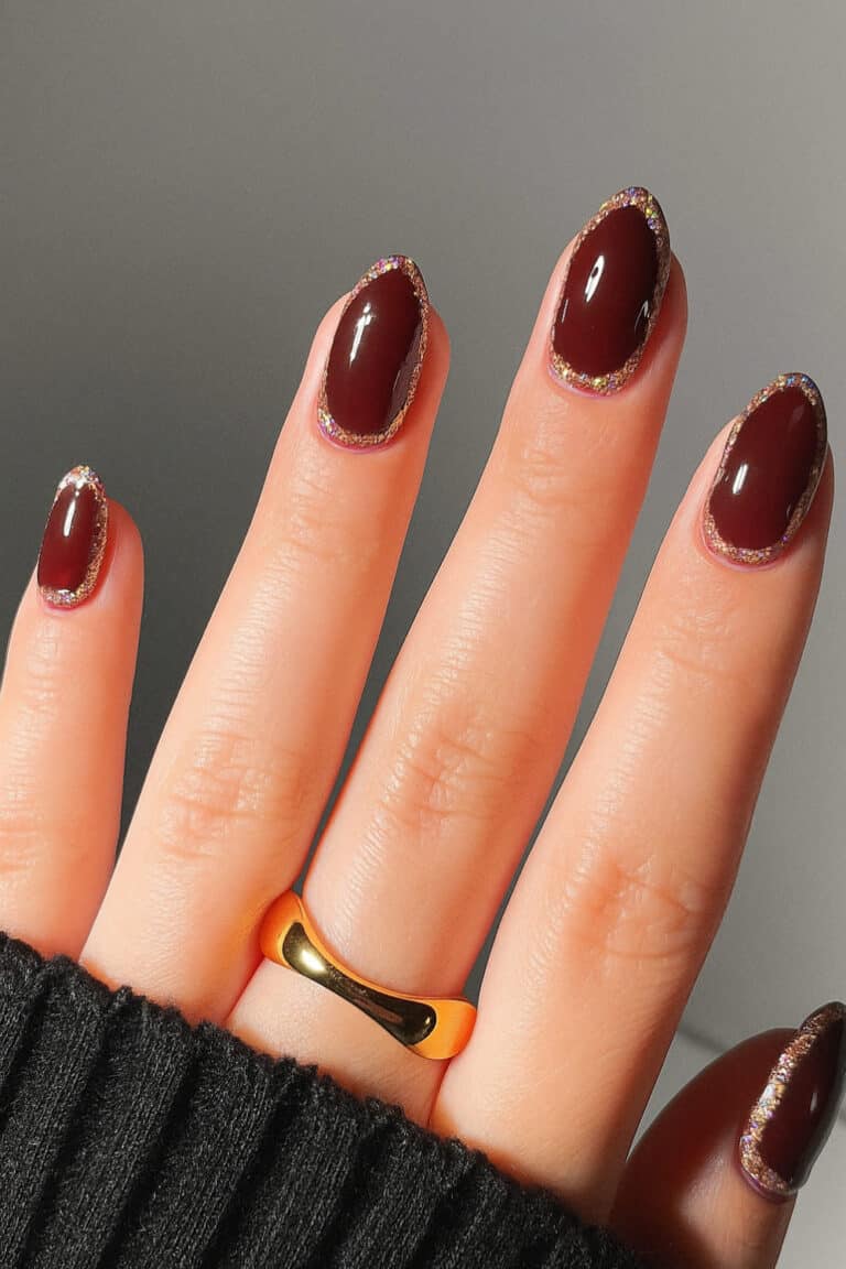 Deep glossy dark cherry nails with a fine glitter outline accent