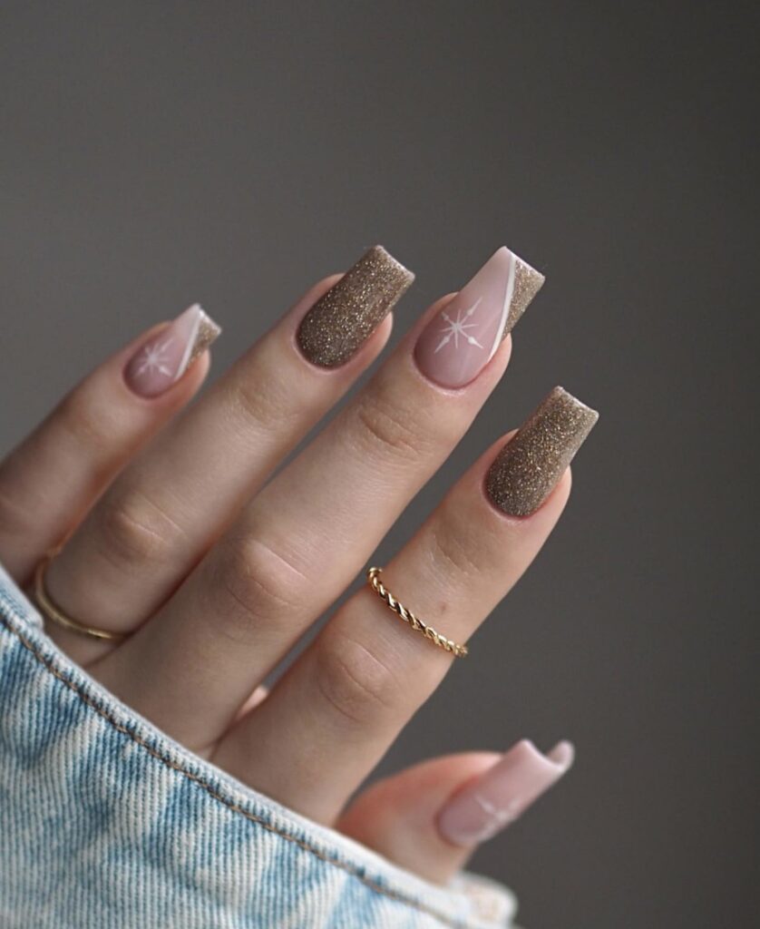 Short winter nails featuring a brown base with white snowflake accents and slanted tips.