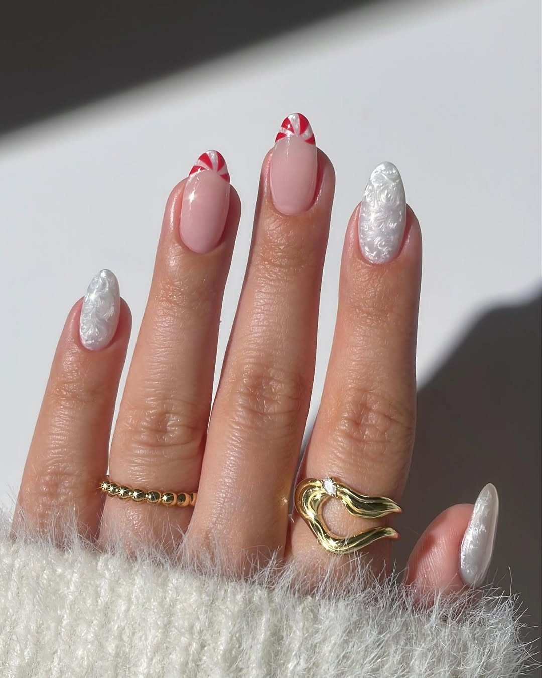 Nude base with red peppermint French tips and pearly white nails.