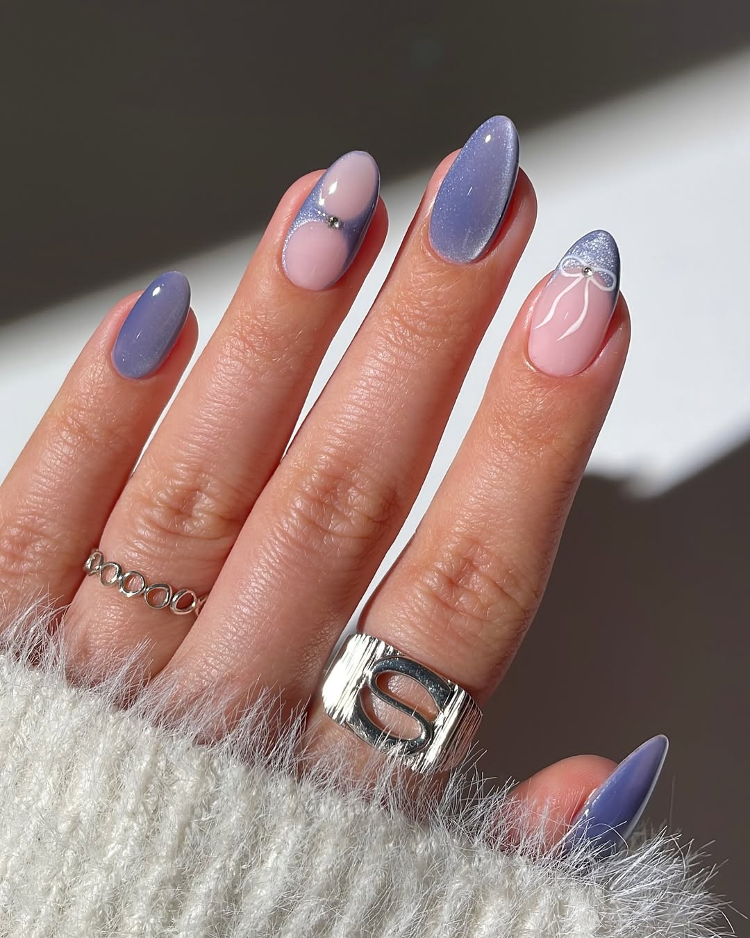 Lilac cat eye nails with blush accents and silver studs.