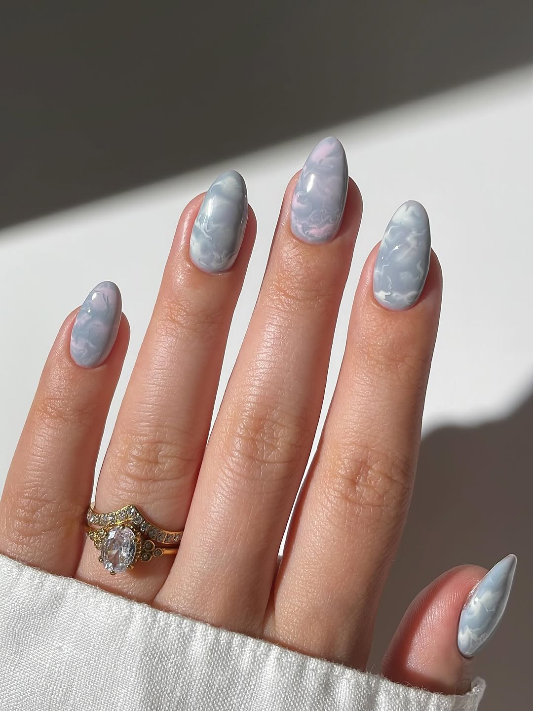 Icy blue, grey, and lavender marble nails with a frosted effect.