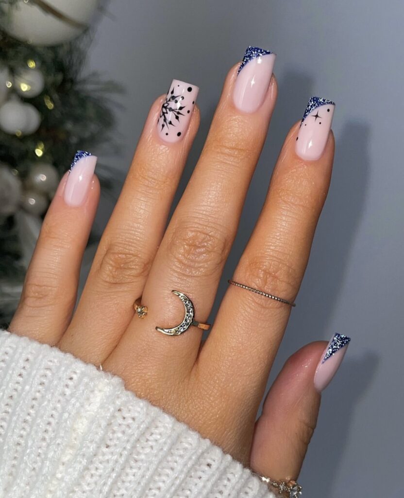 Short square winter nails with dark base, sparkly slanted tips, and snowflake details.