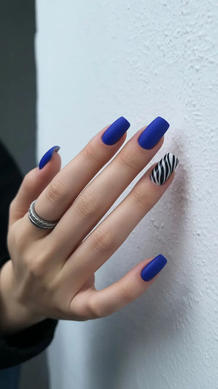 Matte cobalt blue square nails with a zebra print accent.