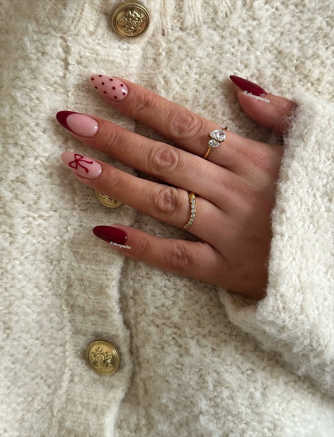 A mix of deep red nails, nude bases, polka dots, a red French tip, and a bow accent.